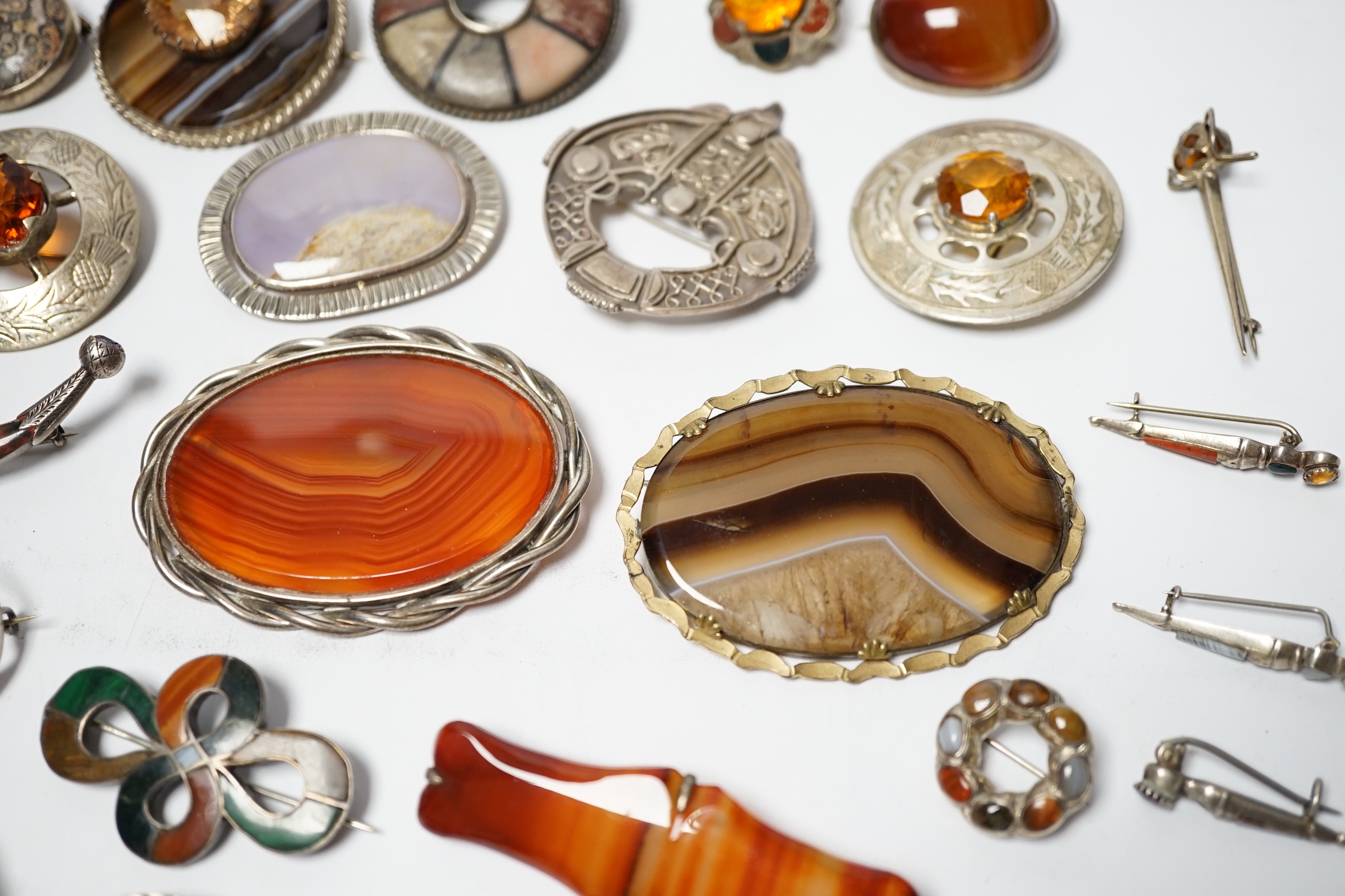 A small collection of mainly silver, sterling and white metal jewellery including Celtic brooches, Iona ship brooch, a Scottish hardstone set bugle brooch and other moss agate set and banded agate set items, largest broo